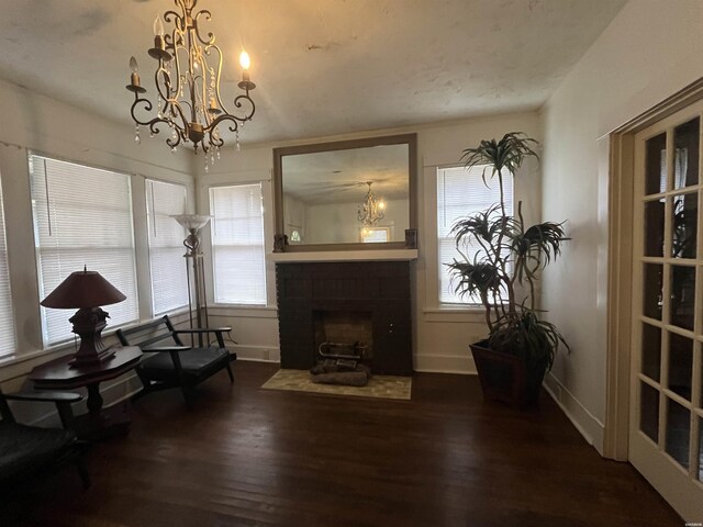 sitting room with dark wood-style floors, a fireplace with flush hearth, baseboards, and an inviting chandelier