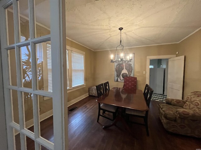 dining space with a notable chandelier, dark wood-type flooring, visible vents, and crown molding