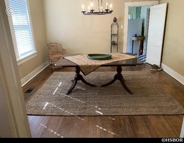 dining space with baseboards, dark wood-type flooring, visible vents, and an inviting chandelier