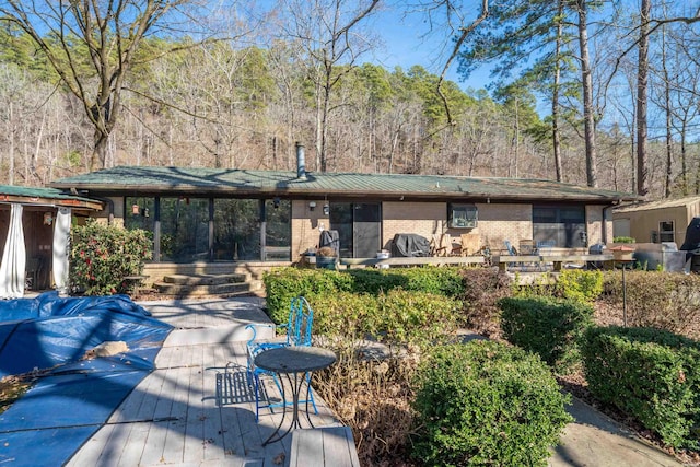 back of property with brick siding and a deck