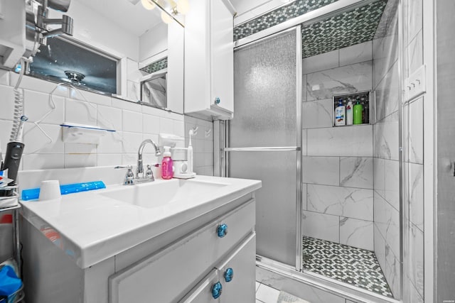 bathroom with backsplash, marble finish floor, vanity, a shower stall, and tile walls