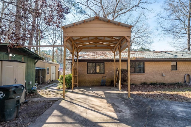 back of property with metal roof, driveway, brick siding, and an outdoor structure