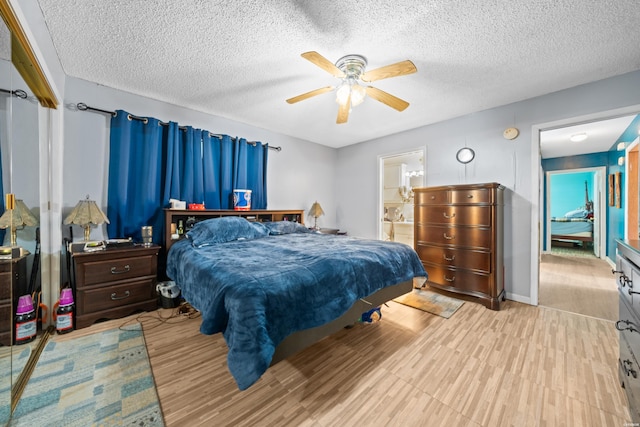 bedroom with baseboards, ceiling fan, ensuite bathroom, a textured ceiling, and light wood-style floors