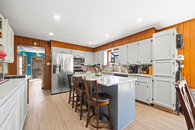 kitchen with appliances with stainless steel finishes, light wood-type flooring, white cabinets, and a kitchen island