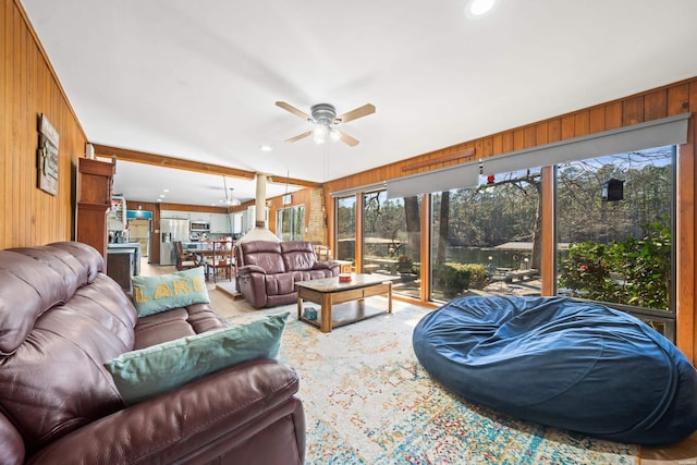 living room with wood walls, a ceiling fan, and recessed lighting