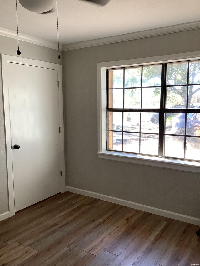 interior space featuring baseboards, a closet, ornamental molding, and dark wood-style flooring