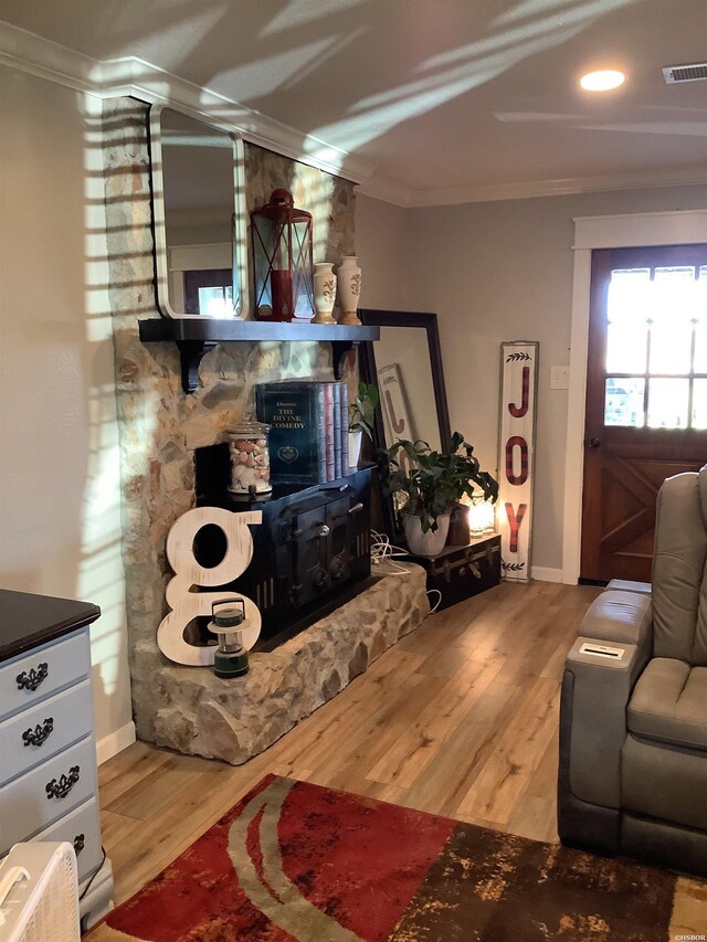 living area featuring ornamental molding, wood finished floors, and visible vents