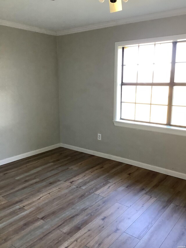 empty room featuring baseboards, ornamental molding, and dark wood-type flooring