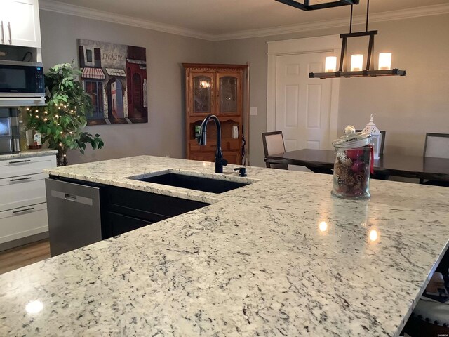 kitchen with decorative light fixtures, stainless steel appliances, white cabinetry, a sink, and light stone countertops