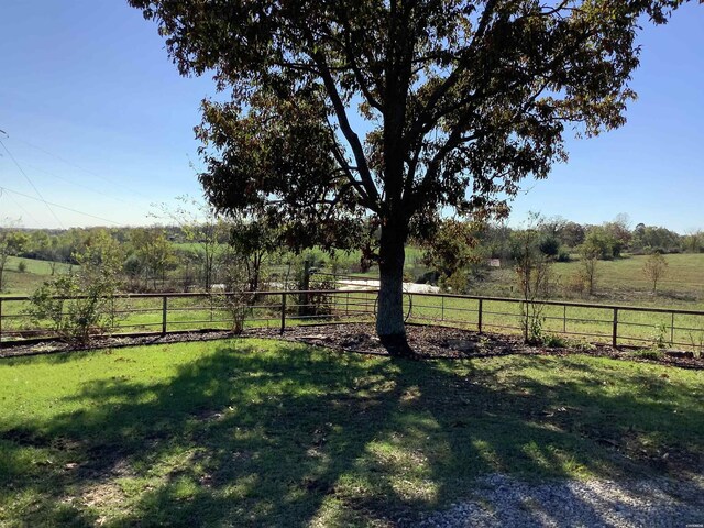 view of yard with fence and a rural view