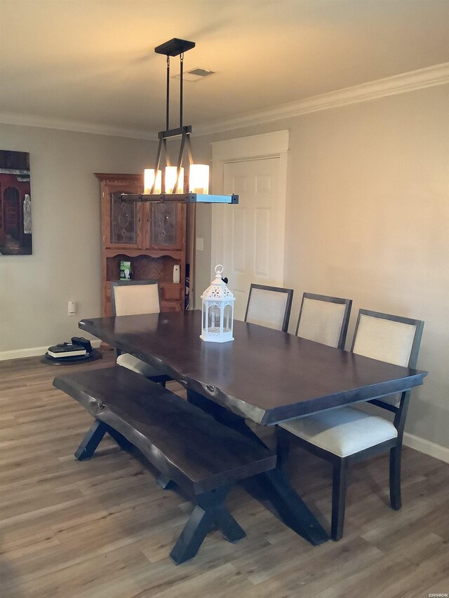 dining space with crown molding, baseboards, and wood finished floors