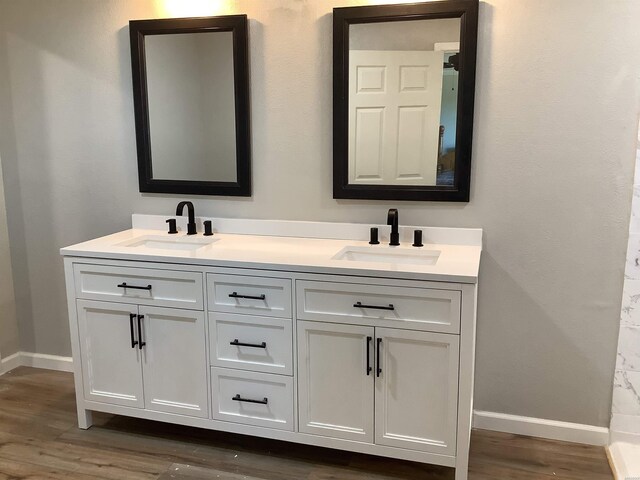 full bathroom featuring double vanity, a sink, and baseboards