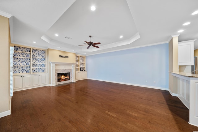 121 Gardens Gate Dr, Hot Springs, AR 71913 - unfurnished living room featuring a tray ceiling, a fireplace with flush hearth, crown molding, dark wood finished floors, and ceiling fan