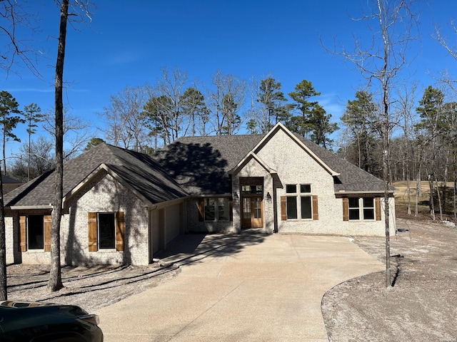 view of front of house with an attached garage, a shingled roof, concrete driveway, and brick siding