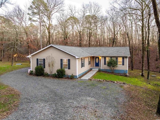 ranch-style house featuring gravel driveway and a shingled roof