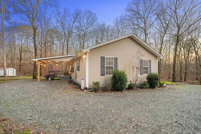 view of property exterior with a storage shed, driveway, and an outbuilding