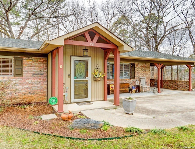 property entrance featuring a shingled roof and brick siding