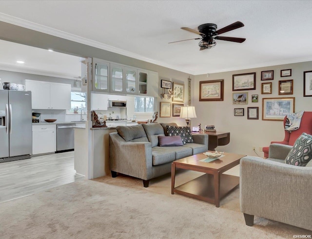 living room featuring a ceiling fan, crown molding, and light colored carpet