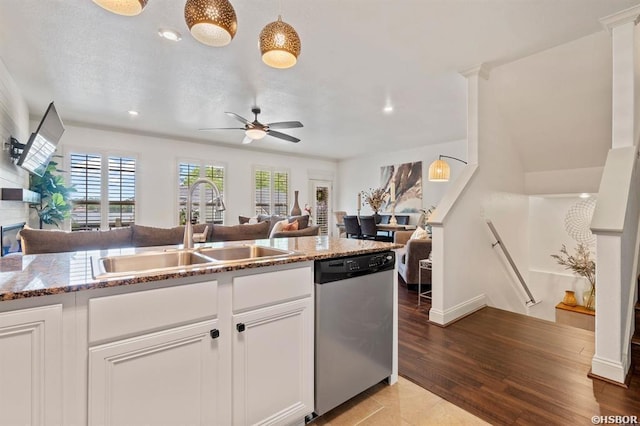 kitchen with a ceiling fan, stone countertops, open floor plan, a sink, and dishwasher