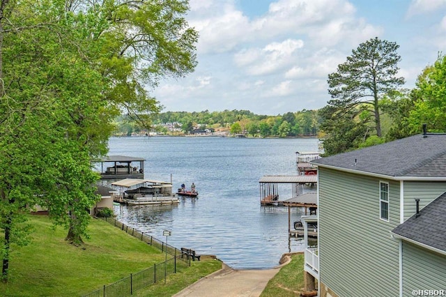 view of dock with fence, a water view, and a yard