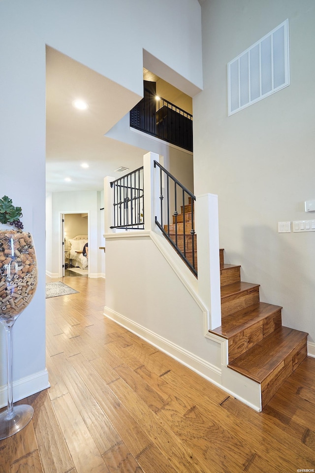 stairway featuring recessed lighting, visible vents, baseboards, and wood finished floors