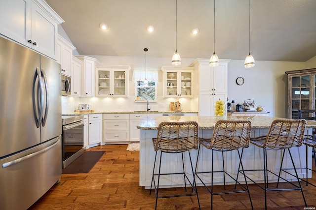 kitchen featuring dark wood-style floors, vaulted ceiling, a breakfast bar area, and stainless steel appliances