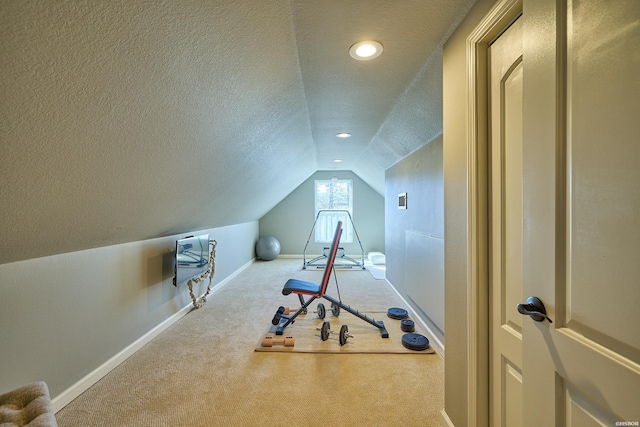 exercise room with vaulted ceiling, a textured ceiling, carpet flooring, and baseboards