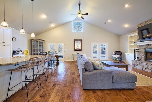 living room featuring high vaulted ceiling, a fireplace, wood finished floors, visible vents, and french doors