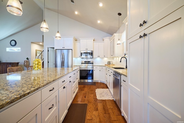 kitchen featuring light stone counters, appliances with stainless steel finishes, dark wood-style flooring, white cabinetry, and a sink