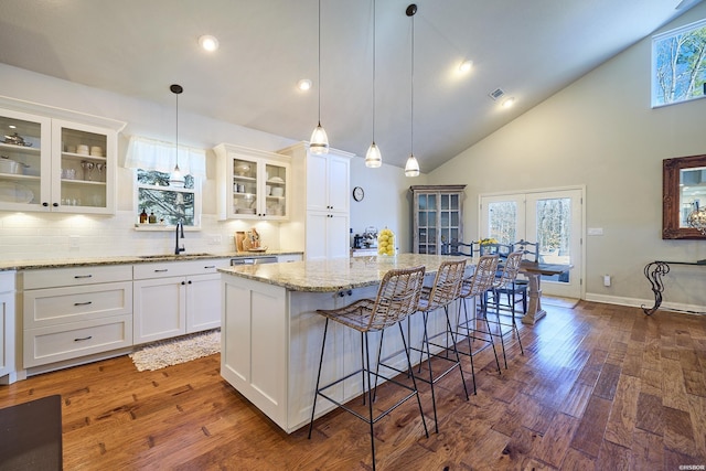 kitchen with dark wood-style flooring, a sink, white cabinets, and a center island