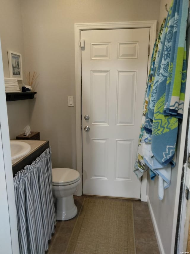 bathroom featuring baseboards, vanity, toilet, and tile patterned floors