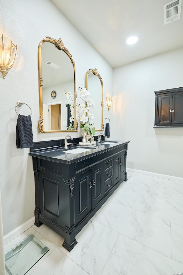 bathroom featuring marble finish floor, double vanity, visible vents, a sink, and baseboards