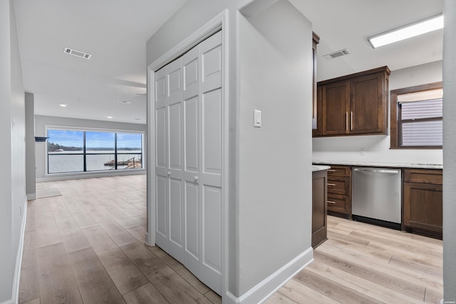 hall featuring baseboards, visible vents, and light wood finished floors