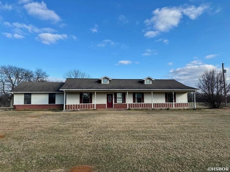 single story home featuring covered porch, brick siding, and a front yard