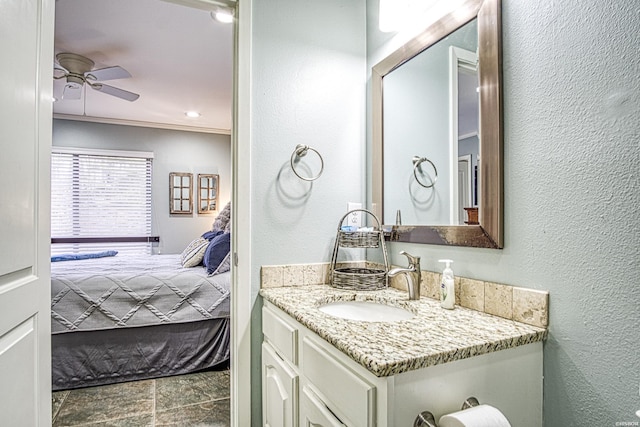 bathroom featuring ceiling fan, a textured wall, vanity, ensuite bath, and crown molding