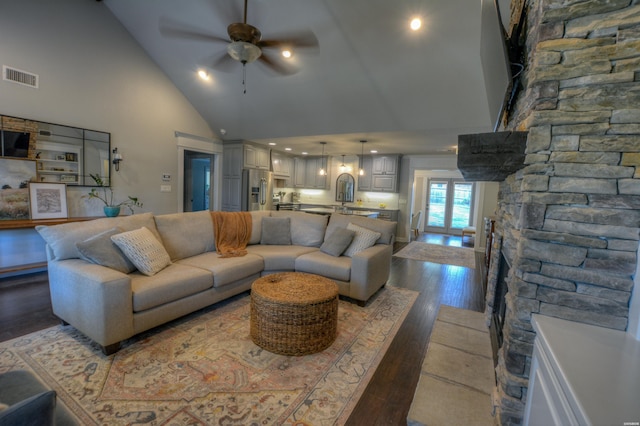 living area with dark wood-style floors, visible vents, ceiling fan, and high vaulted ceiling