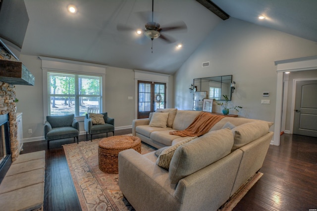 living room featuring dark wood-style flooring, visible vents, a stone fireplace, high vaulted ceiling, and beamed ceiling