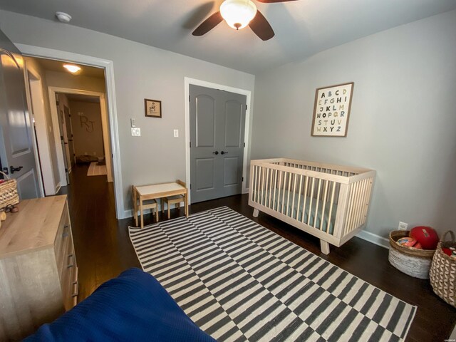 bedroom with dark wood-type flooring, a ceiling fan, and baseboards