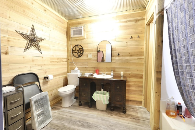 full bath featuring wooden walls, toilet, wood finished floors, vanity, and a wall mounted AC