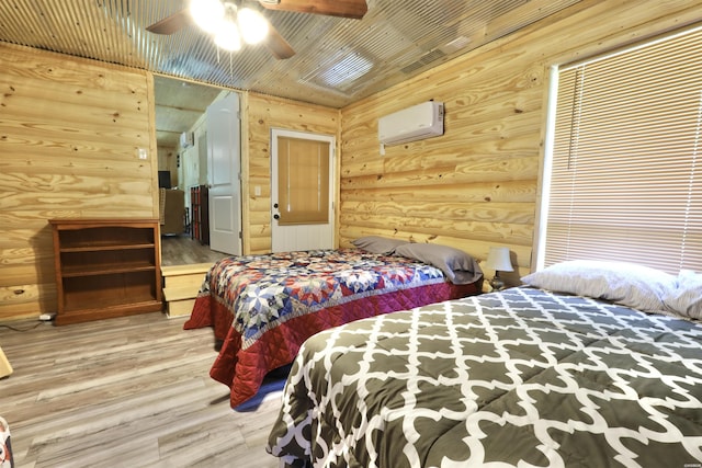 bedroom with ceiling fan, wooden ceiling, wood finished floors, a wall mounted AC, and log walls