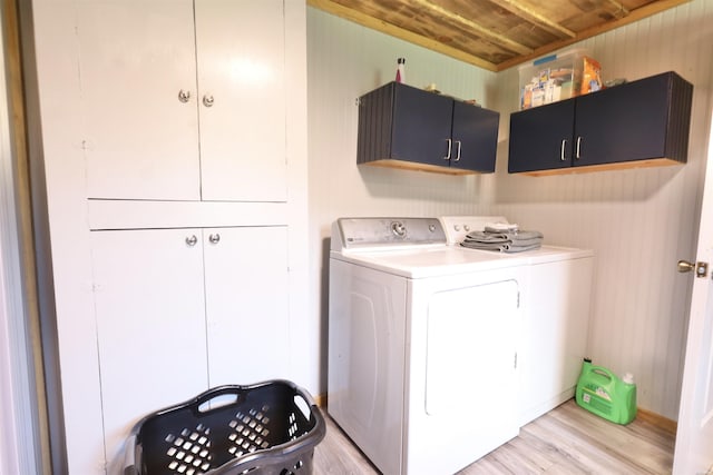 clothes washing area featuring wooden ceiling, cabinet space, light wood-style flooring, and washer and clothes dryer