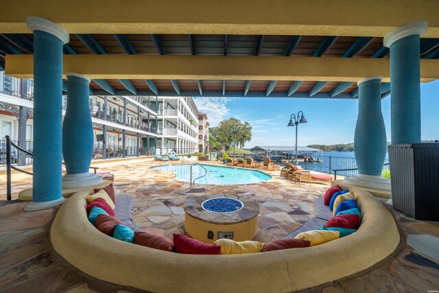 community pool featuring a fire pit, a patio, and a water view