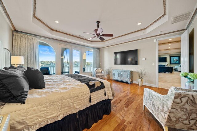 bedroom with access to exterior, a tray ceiling, french doors, visible vents, and light wood-type flooring