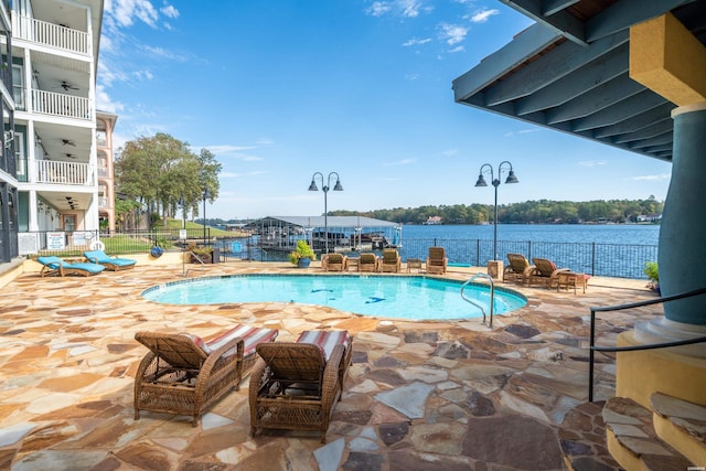 pool with ceiling fan, a patio, a water view, and fence