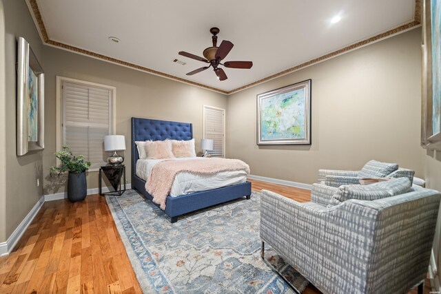 bedroom featuring a ceiling fan, baseboards, ornamental molding, and wood finished floors