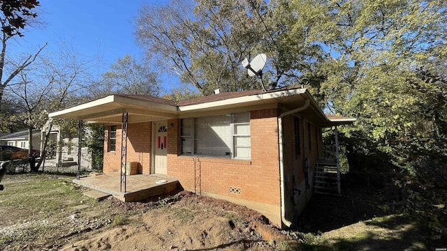 view of side of home with crawl space, brick siding, and fence