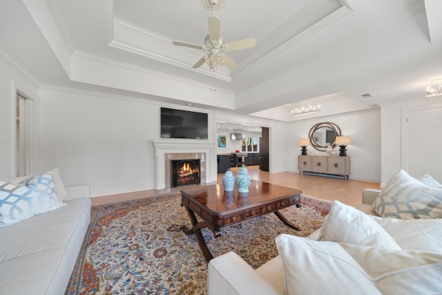 living room with ornamental molding, a tray ceiling, wood finished floors, a fireplace, and baseboards