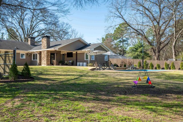 back of property featuring a fenced in pool, a lawn, a chimney, a fenced backyard, and a patio