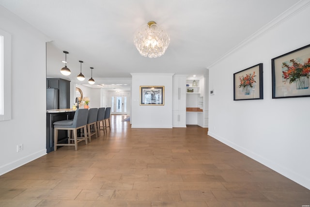 interior space with an inviting chandelier, crown molding, wood finished floors, and baseboards