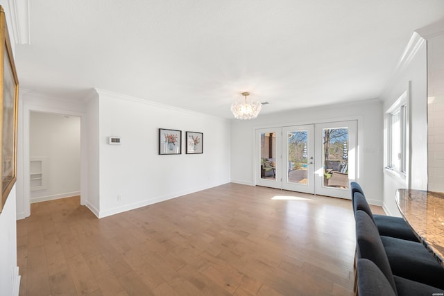 unfurnished living room with a notable chandelier, wood finished floors, and ornamental molding